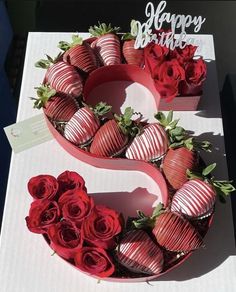 two heart shaped chocolate covered strawberries with roses in the shape of number 2 on a table