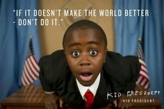 a young boy wearing a suit and red tie with an american flag behind him in front of a desk