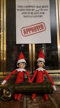 two elfs sitting in front of a sign that says approved