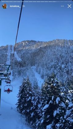 a ski lift going up the side of a snow covered mountain with trees on it