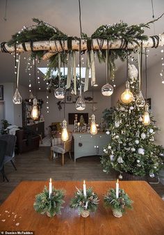 christmas decorations are hanging from the ceiling above a table with candles and greenery on it