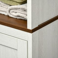 towels are stacked on top of each other in the corner of a cabinet with drawers