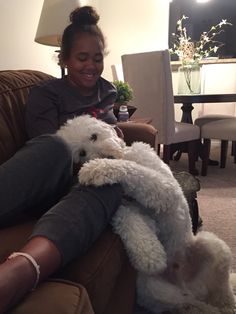 a woman sitting on a couch holding a stuffed animal in her lap and smiling at the camera