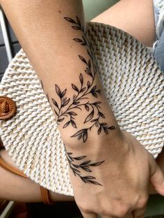 a woman's arm with black leaves on it