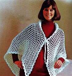 a woman is wearing a white crocheted shawl and red sweater, she has her hands on her hips