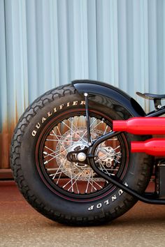 a red and black motorcycle parked next to a metal building with a blue wall behind it