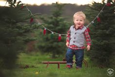 a young boy standing in front of a christmas tree