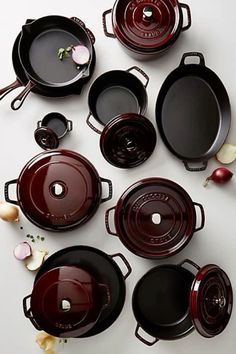 many pots and pans are arranged on a white surface with onions in the middle