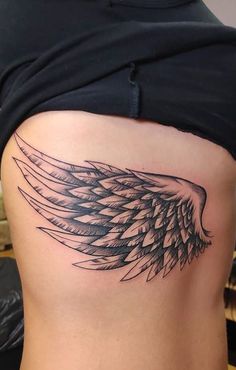 a woman's lower back with an angel wing tattoo on her left side ribcage