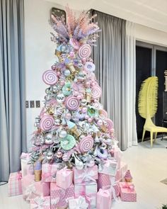 a pink christmas tree decorated with lollipops and other candies in pastel colors