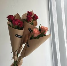 three roses are wrapped in brown paper and tied together