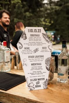 a wooden table topped with lots of bottles and glasses next to a sign that says cocktails