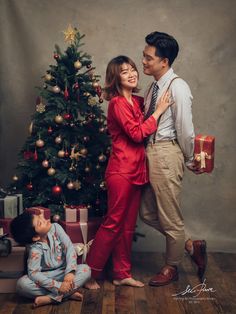 a man and woman standing next to a christmas tree