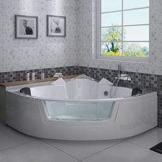 a large white bath tub sitting in a bathroom next to a sink and window with pictures on the wall