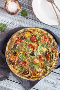 a pizza sitting on top of a wooden table next to a plate and spoons