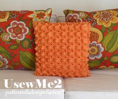 two decorative pillows sitting on top of a white couch