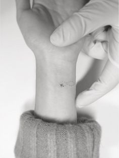 a woman's wrist with a small tattoo on the left side of her arm