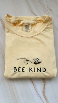 Baby yellow embroidered Comfort Colors short sleeve t-shirt with a bee and phrase "Bee Kind"  Each item is made to order so slight variations may occur Yellow Cotton Top With Embroidered Logo, Yellow Crew Neck Tops With Embroidered Logo, Casual Yellow Embroidered T-shirt, Casual Yellow T-shirt With Embroidered Graphics, Yellow Cotton T-shirt With Embroidered Graphics, Yellow Casual T-shirt With Embroidered Graphics, Yellow Embroidered Short Sleeve T-shirt, Bee Kind, Yellow T Shirt