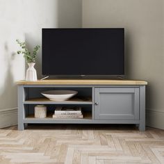 a television stand with a bowl and vase on it in front of a white wall