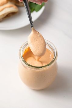 a person dipping something into a jar with a spoon