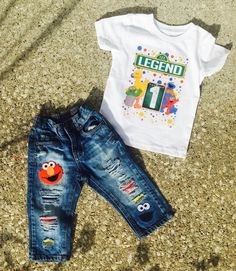 a white shirt and jeans are on the ground next to a sesame character t - shirt