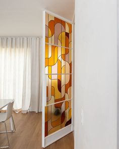 an open door leading to a dining room with white walls and wooden flooring that has stained glass panels on it