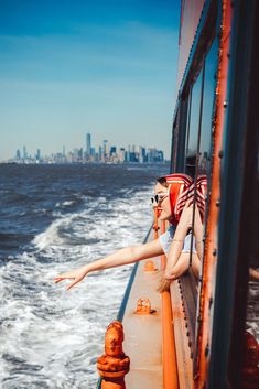 a woman leaning on the side of a boat with her arms out and legs stretched out