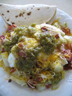 a white plate topped with an egg burrito and salsa