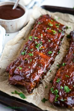 ribs covered in bbq sauce and garnished with parsley on parchment paper