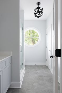 a white bathroom with a round window and tile floor