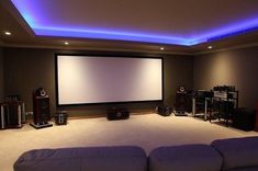 a large screen in the middle of a room with couches and speakers on either side