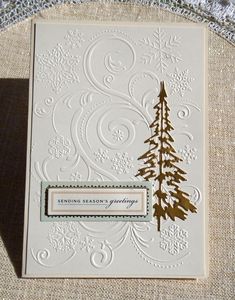 a white card with gold foiling and a pine tree on the front, surrounded by snowflakes