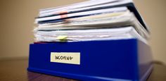 a stack of papers sitting on top of a blue file box with a name tag