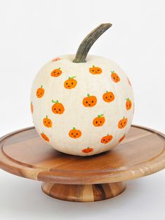 an orange painted pumpkin sitting on top of a wooden stand