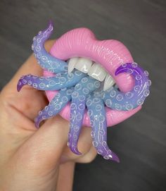 a person holding an octopus toothbrush holder in their hand with purple and blue decorations on it