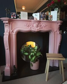 a pink fireplace with a potted plant on top