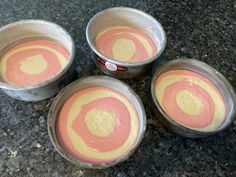 four metal bowls filled with batter sitting on top of a granite counter next to each other