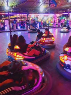 several people riding bumper cars in an amusement park at night with colorful lights on them