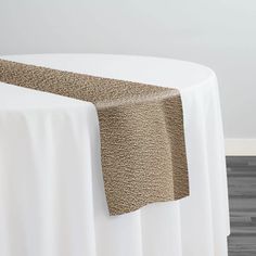 a table with a white cloth on it and a brown place mat under the edge