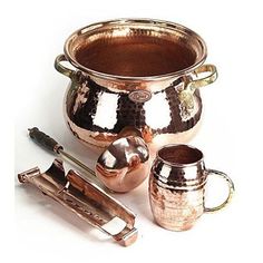 a large metal pot with two mugs next to it and some other utensils