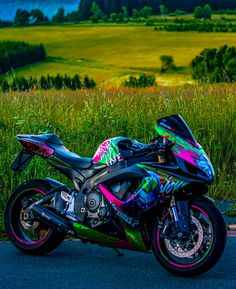 a colorful motorcycle is parked on the side of the road in front of some tall grass