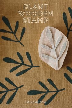 a plant wooden stamp sitting on top of a brown cloth with green leaves and the words, plant wooden stamp