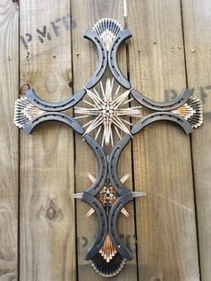 a cross made out of metal on top of a wooden fence