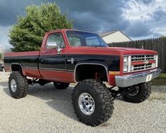 a red and black truck is parked in the gravel