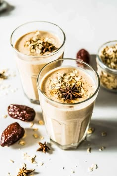 two glasses filled with desserts on top of a white table next to nuts and other food