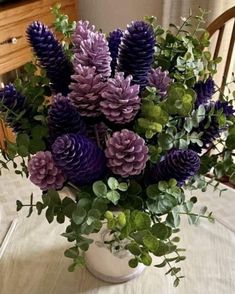 purple and green flowers in a white vase on a table