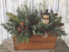 a wooden box filled with evergreen and pine cones