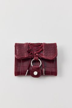 a small red purse with a ring on the front and an alligator skin strap around it