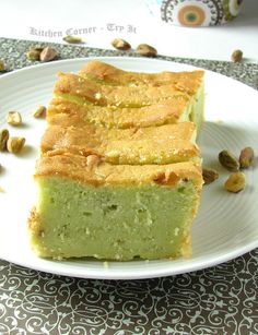 a white plate topped with slices of cake next to pistachios on a table