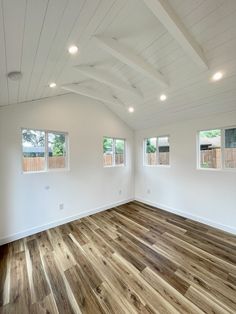 an empty room with wood flooring and three windows in the ceiling, all white